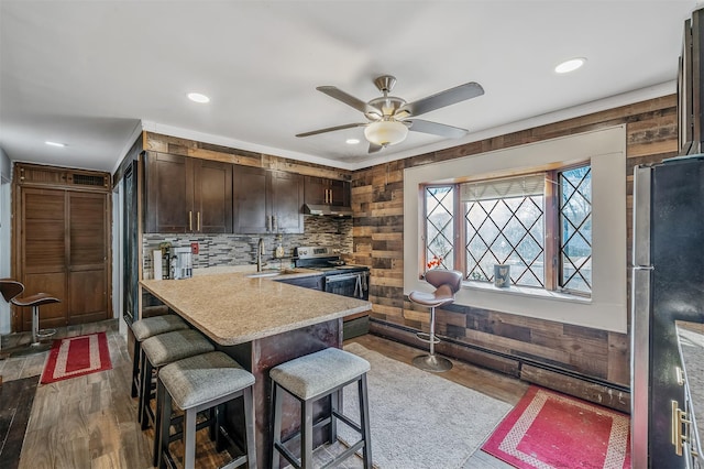 kitchen with a kitchen bar, wood-type flooring, sink, appliances with stainless steel finishes, and dark brown cabinets