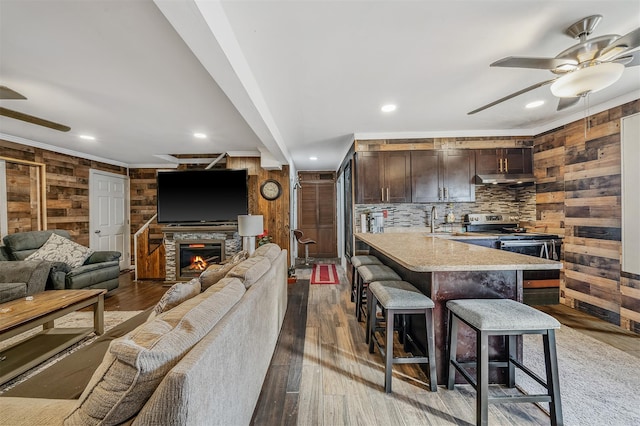 kitchen with ceiling fan, dark brown cabinets, stainless steel range with electric cooktop, and a breakfast bar area