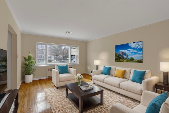 living room featuring light wood-type flooring, radiator heating unit, and ornamental molding