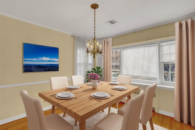 dining room with a chandelier, light wood-type flooring, a wealth of natural light, and ornamental molding