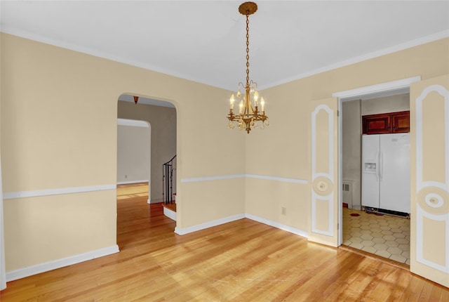 unfurnished room featuring an inviting chandelier, ornamental molding, and light wood-type flooring