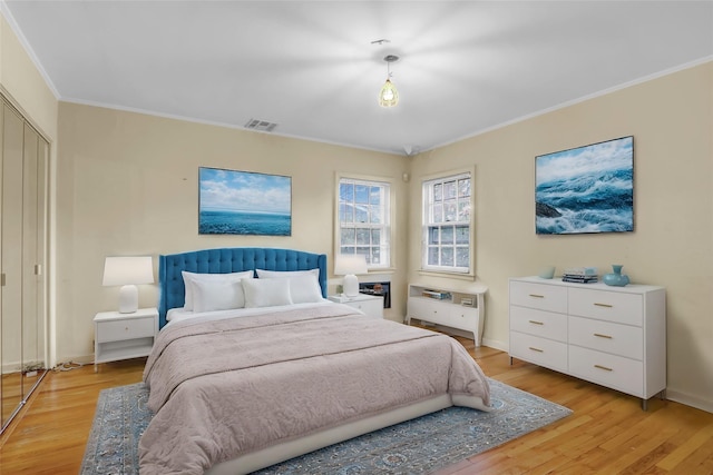 bedroom with light wood-type flooring, a closet, and crown molding