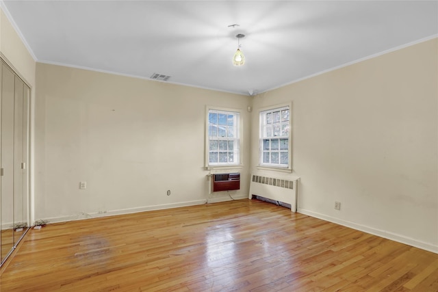 empty room with radiator heating unit, light hardwood / wood-style floors, heating unit, and crown molding