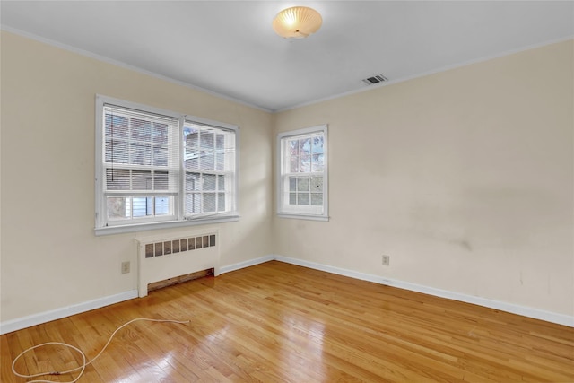 unfurnished room with hardwood / wood-style floors, radiator heating unit, and crown molding