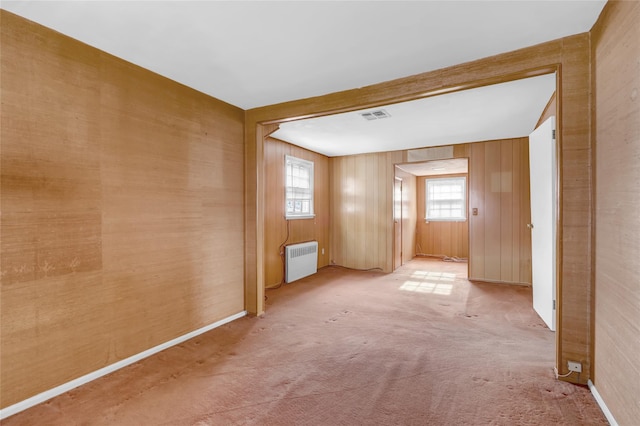 carpeted spare room with radiator heating unit and wooden walls