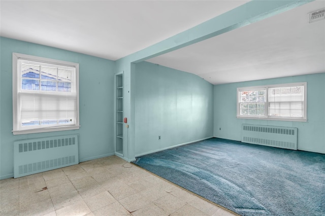 empty room with lofted ceiling, radiator heating unit, and a wealth of natural light