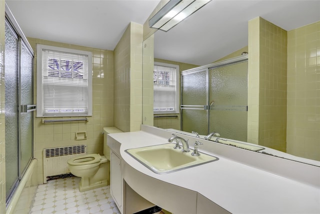 full bathroom with radiator, a healthy amount of sunlight, tile walls, and toilet