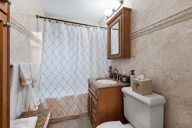 bathroom featuring vanity, tile walls, and toilet