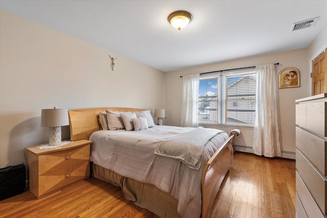 bedroom featuring baseboard heating and light hardwood / wood-style flooring