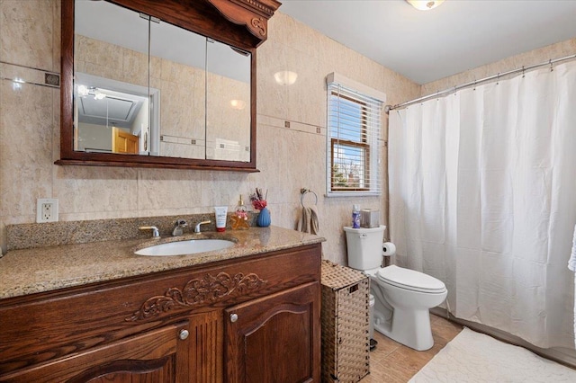 bathroom with tile patterned flooring, vanity, toilet, and tile walls