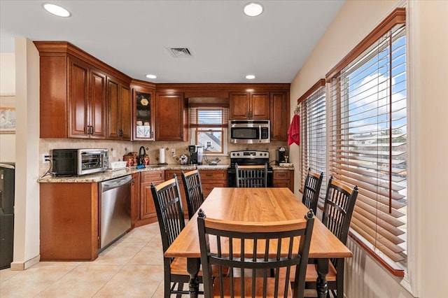 kitchen featuring light stone countertops, appliances with stainless steel finishes, a healthy amount of sunlight, and light tile patterned flooring