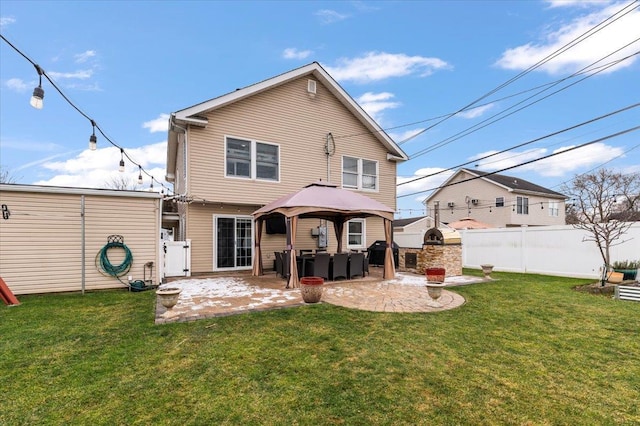 back of property with a gazebo, a patio area, a fireplace, and a lawn