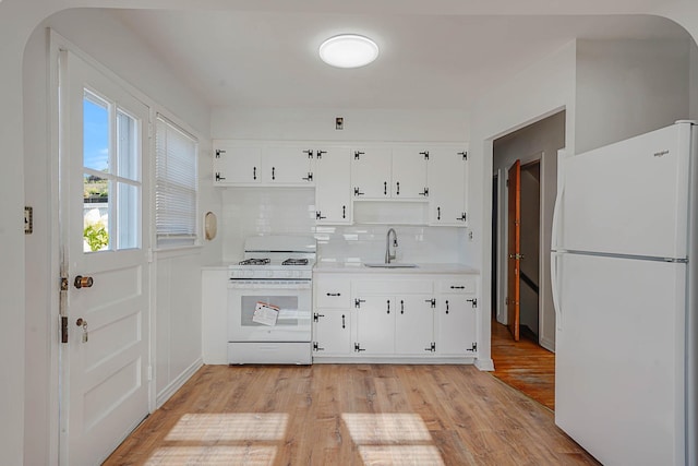 kitchen featuring white cabinetry, backsplash, white appliances, light hardwood / wood-style flooring, and sink