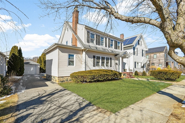 view of front of house featuring a garage, a front yard, a chimney, and an outdoor structure