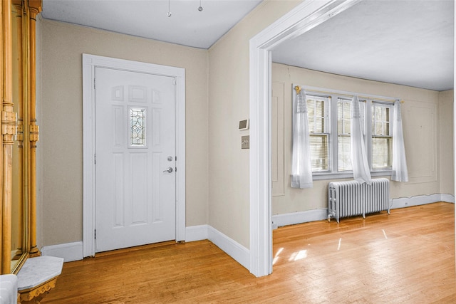 foyer with light wood-type flooring, radiator, and baseboards