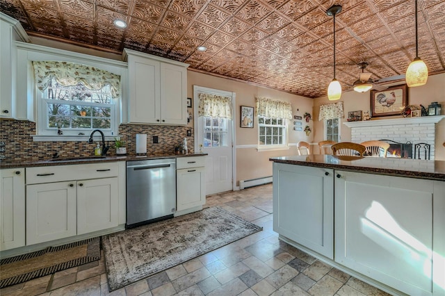 kitchen with hanging light fixtures, sink, white cabinetry, stainless steel dishwasher, and a baseboard radiator