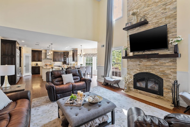 living room with an inviting chandelier, a fireplace, and wood-type flooring