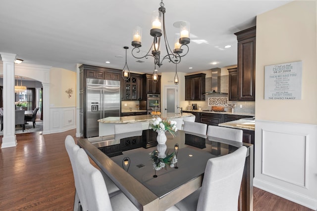 dining space with a notable chandelier, ornate columns, and dark hardwood / wood-style floors