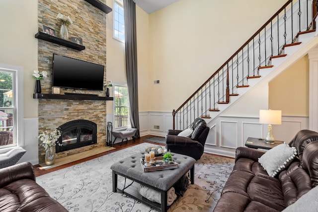 living room featuring light hardwood / wood-style floors, a high ceiling, and a stone fireplace