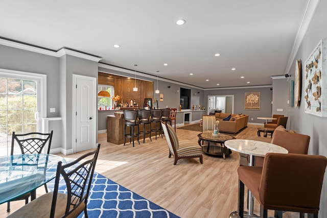 dining room with crown molding, indoor bar, and light wood-type flooring