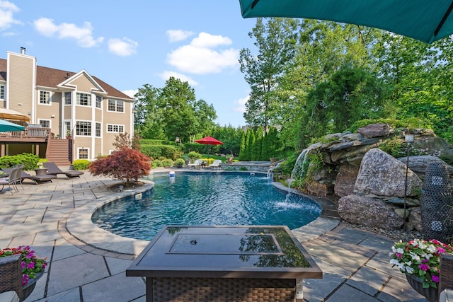 view of pool featuring pool water feature, an outdoor fire pit, and a patio