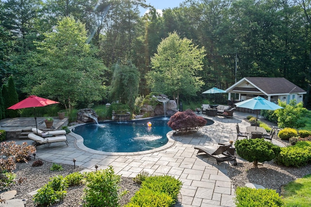 view of pool with a patio area, an outdoor structure, and pool water feature