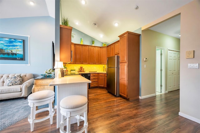 kitchen with a breakfast bar area, stainless steel refrigerator, kitchen peninsula, and lofted ceiling