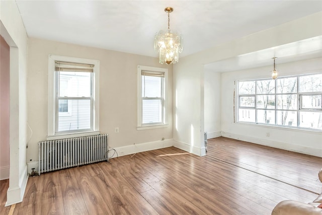 unfurnished room with a notable chandelier, wood-type flooring, and radiator