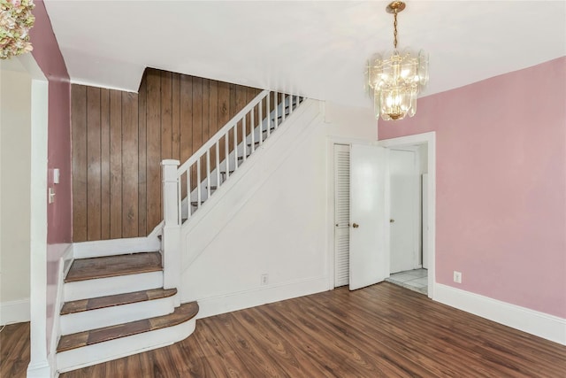 staircase featuring wooden walls, hardwood / wood-style floors, and a chandelier