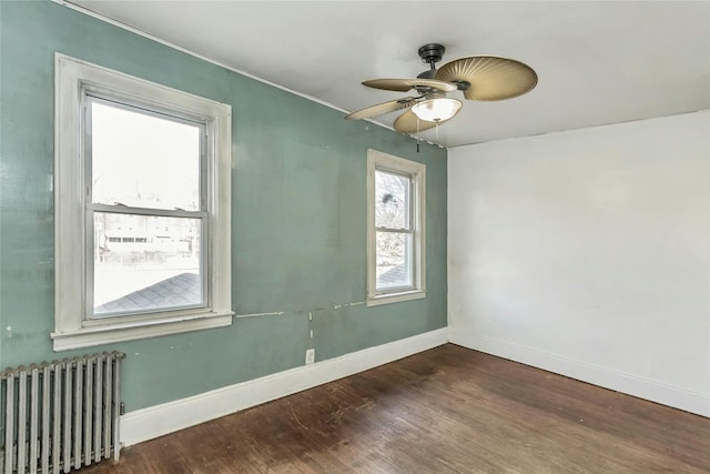 empty room featuring radiator, ceiling fan, and dark hardwood / wood-style flooring