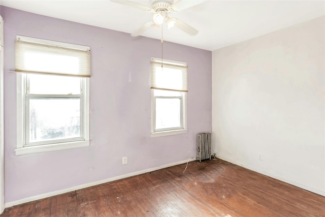 unfurnished room with dark wood-type flooring, radiator, a healthy amount of sunlight, and ceiling fan