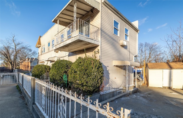 view of side of property featuring a storage shed and a balcony