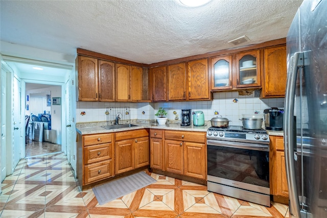 kitchen featuring a textured ceiling, stainless steel appliances, tasteful backsplash, and sink