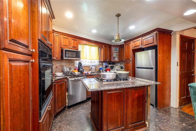 kitchen with hanging light fixtures, crown molding, dark stone counters, a kitchen island, and appliances with stainless steel finishes