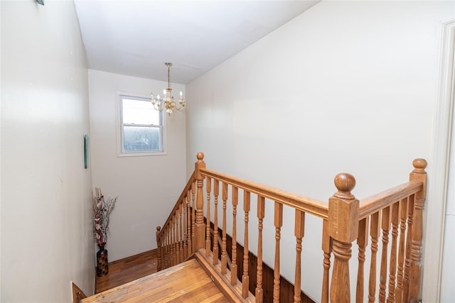 staircase featuring hardwood / wood-style flooring and a notable chandelier