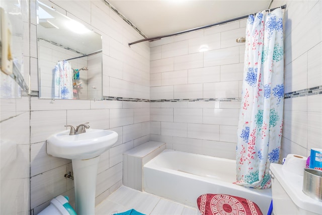 bathroom with sink, shower / bathtub combination with curtain, and tile walls