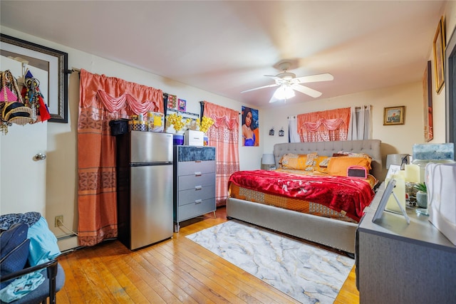 bedroom featuring stainless steel fridge, ceiling fan, and light wood-type flooring