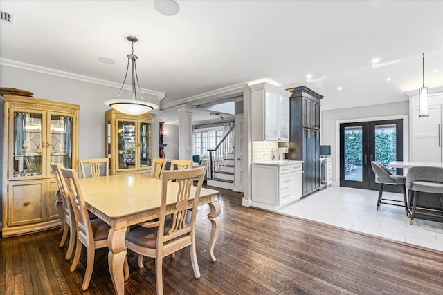 dining space with decorative columns, ornamental molding, french doors, and light wood-type flooring