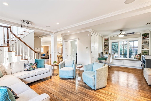 living room with ceiling fan, wood-type flooring, decorative columns, and ornamental molding