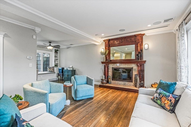 living room featuring a high end fireplace, wood-type flooring, built in features, ornamental molding, and ceiling fan