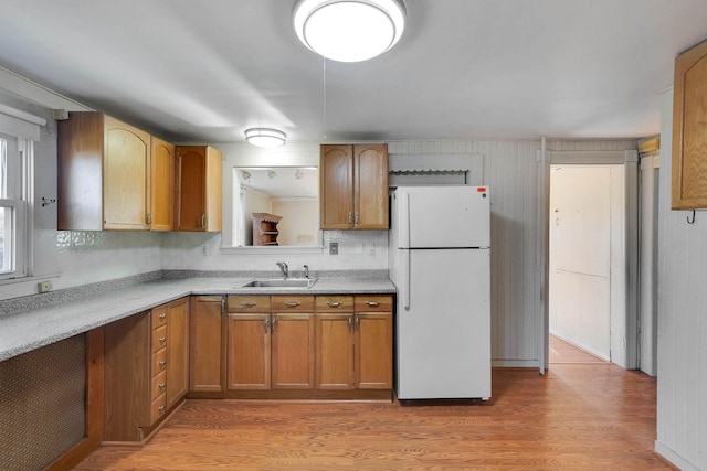 kitchen featuring sink, white refrigerator, tasteful backsplash, and light wood-type flooring