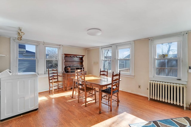 dining space featuring washer / clothes dryer, light wood-type flooring, plenty of natural light, and radiator heating unit