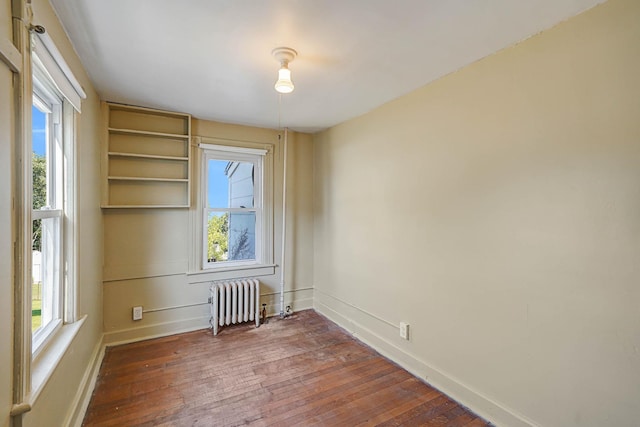 spare room featuring dark wood-type flooring and radiator