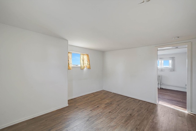 unfurnished room featuring dark wood-type flooring and a healthy amount of sunlight