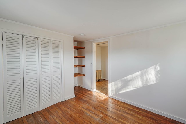 unfurnished bedroom featuring radiator, crown molding, and hardwood / wood-style floors