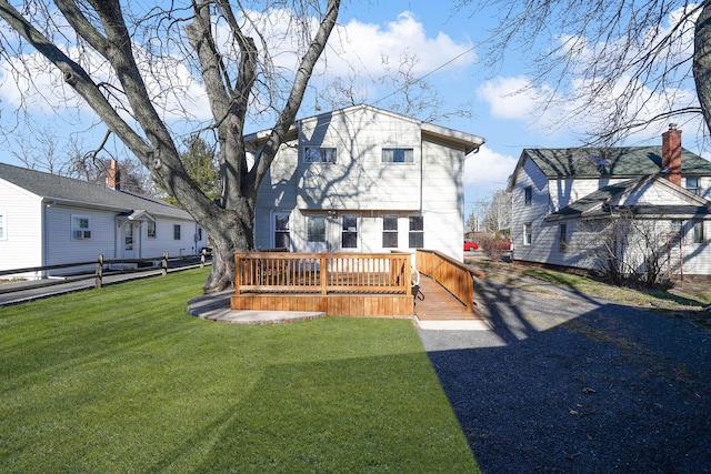 back of property featuring a wooden deck and a lawn