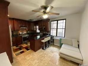 kitchen with ceiling fan, a breakfast bar area, and electric stove