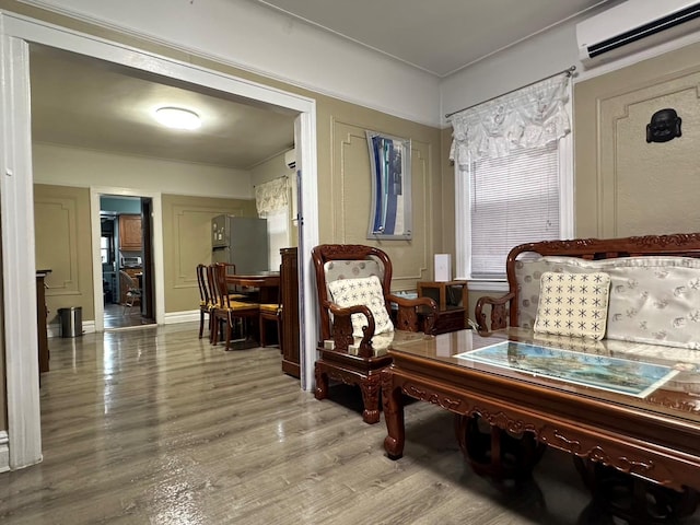 living area featuring wood-type flooring and an AC wall unit