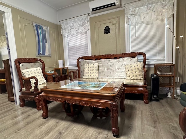 sitting room with wood-type flooring and a wall mounted AC