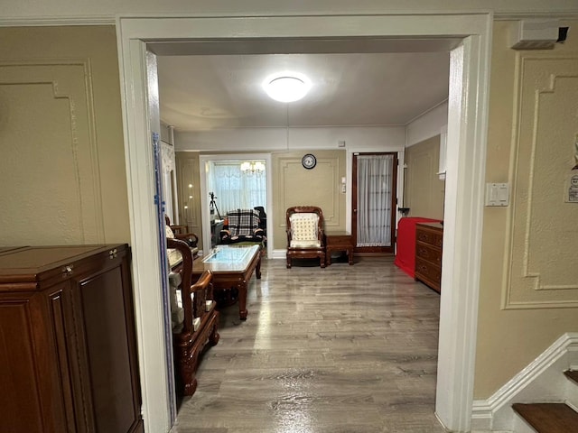 corridor with a notable chandelier and light wood-type flooring